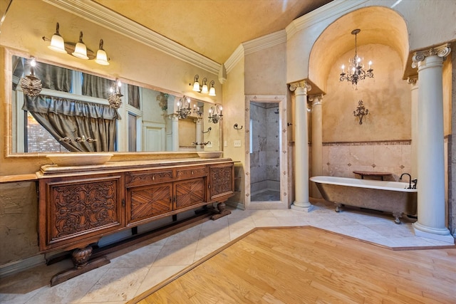 bathroom featuring vanity, shower with separate bathtub, hardwood / wood-style flooring, decorative columns, and crown molding