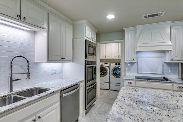 kitchen with washer and clothes dryer, white cabinets, sink, and appliances with stainless steel finishes