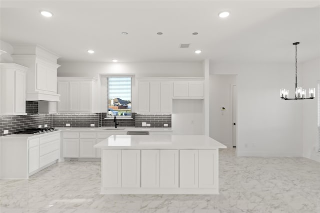 kitchen with white cabinetry, stainless steel gas cooktop, a center island, and sink