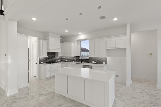 kitchen featuring dishwasher, white cabinetry, a kitchen island, and sink