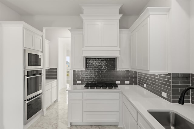 kitchen with appliances with stainless steel finishes, sink, white cabinets, and backsplash