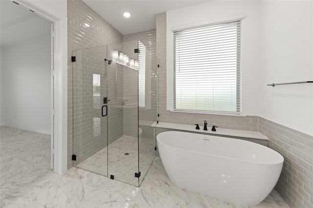 bathroom featuring shower with separate bathtub and tile walls