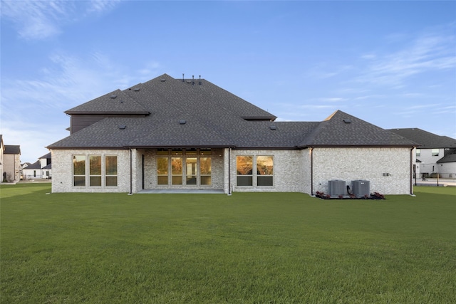 rear view of house with cooling unit and a lawn