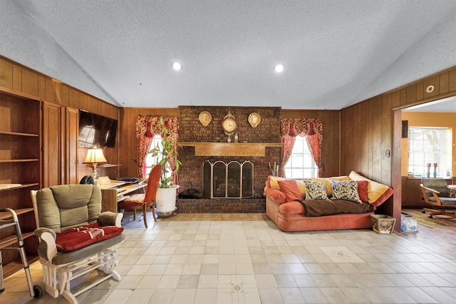 living room with a textured ceiling, wooden walls, a fireplace, and lofted ceiling