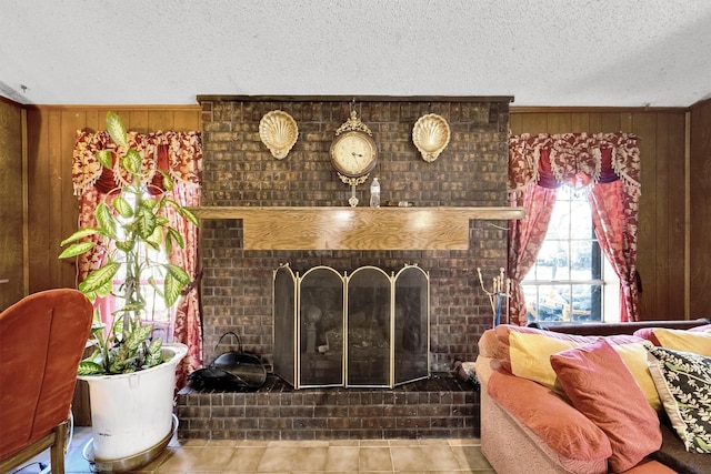 living room featuring a fireplace, a textured ceiling, tile patterned floors, and wood walls