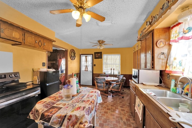 kitchen with a textured ceiling, stainless steel appliances, ceiling fan, and sink