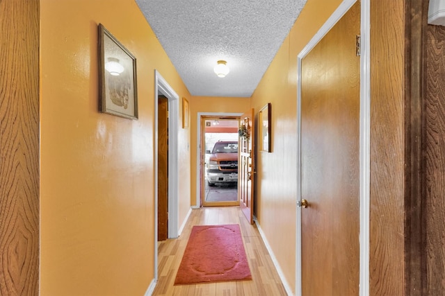 hall featuring light hardwood / wood-style flooring and a textured ceiling