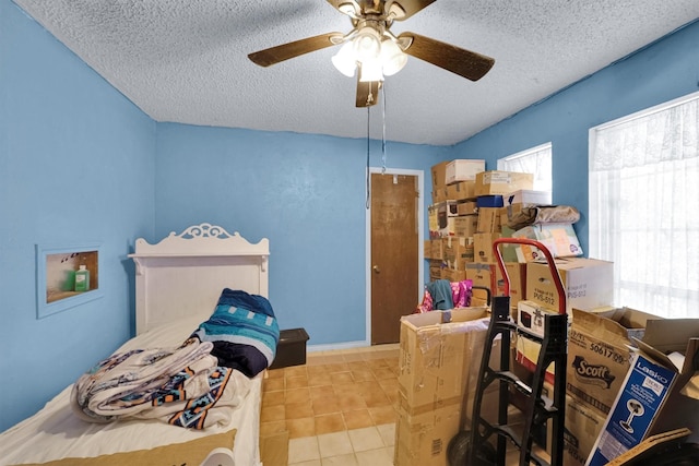 bedroom with ceiling fan, light tile patterned flooring, and a textured ceiling