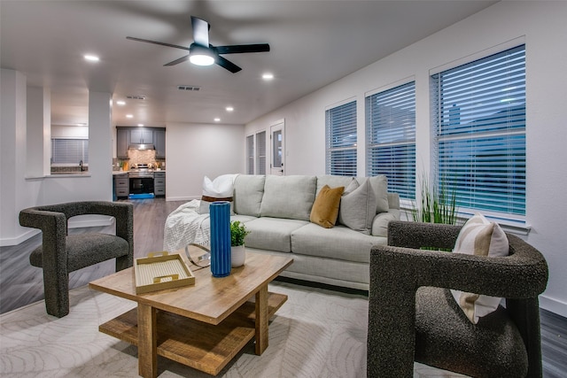 living room featuring ceiling fan, recessed lighting, visible vents, baseboards, and light wood-type flooring