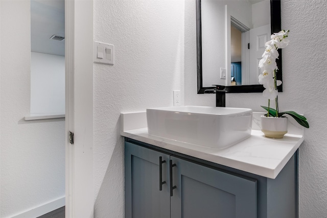 bathroom featuring a textured wall, vanity, and visible vents