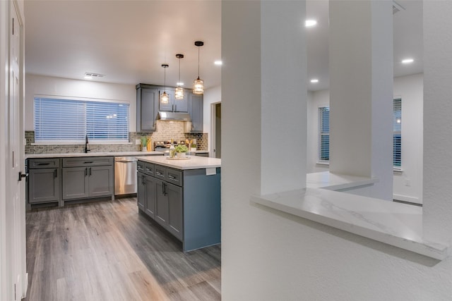 kitchen featuring dark wood-style flooring, decorative light fixtures, stainless steel appliances, decorative backsplash, and under cabinet range hood