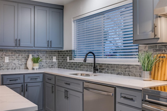 kitchen with gray cabinetry, dishwasher, wall chimney range hood, and a sink