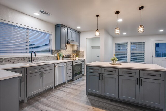 kitchen with decorative light fixtures, stainless steel appliances, visible vents, light countertops, and under cabinet range hood