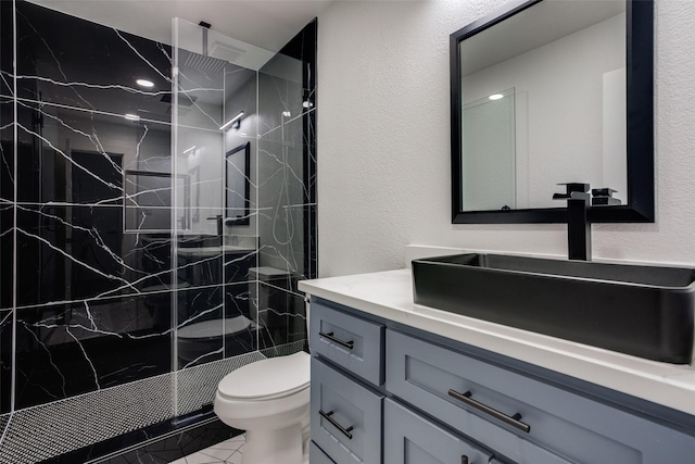 full bath with toilet, a textured wall, a marble finish shower, and vanity