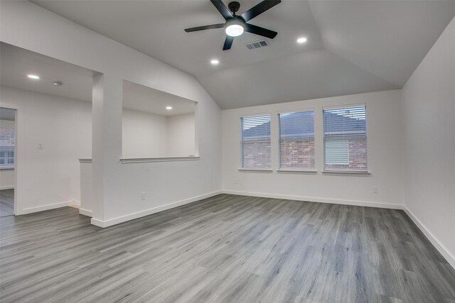 unfurnished room with visible vents, vaulted ceiling, light wood-style flooring, and baseboards