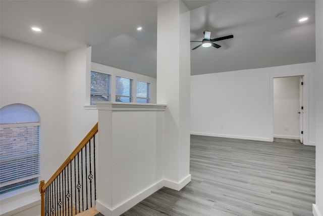 hallway with lofted ceiling, light wood-style floors, baseboards, and recessed lighting