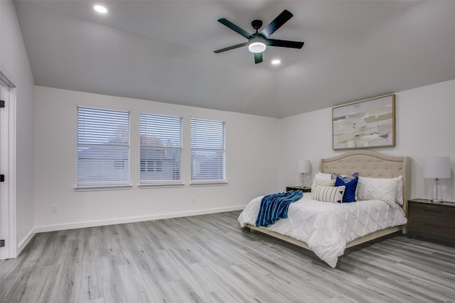 bedroom featuring lofted ceiling, light wood-style flooring, and baseboards