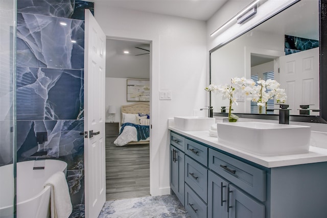 ensuite bathroom featuring ensuite bathroom, double vanity, a freestanding bath, and a sink