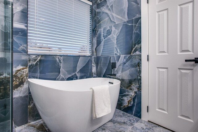 full bath featuring a soaking tub and tile walls