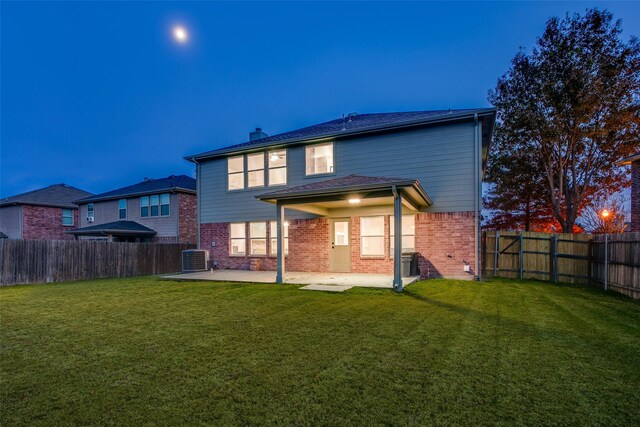 back of property with a fenced backyard, a patio, brick siding, and a lawn