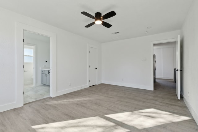 unfurnished bedroom featuring baseboards, freestanding refrigerator, visible vents, and light wood-style floors