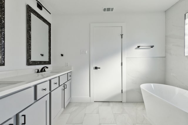 bathroom featuring a freestanding bath, double vanity, a sink, and visible vents