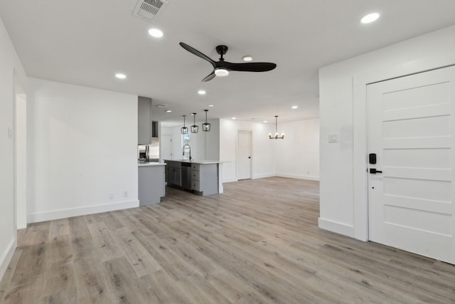 unfurnished living room with ceiling fan with notable chandelier, recessed lighting, visible vents, and light wood-style floors