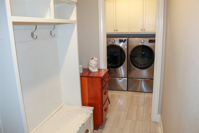 clothes washing area with washer and dryer and cabinets