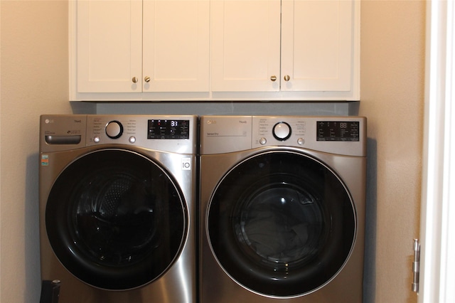 clothes washing area featuring cabinets and washer and clothes dryer