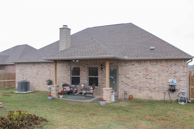 back of house with central AC unit, a patio area, and a lawn