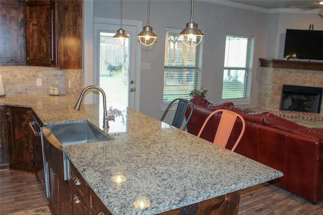 kitchen with a stone fireplace, light stone countertops, sink, and crown molding