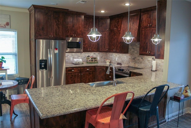 kitchen with pendant lighting, decorative backsplash, sink, and appliances with stainless steel finishes