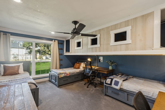 bedroom with ceiling fan, wooden walls, and carpet