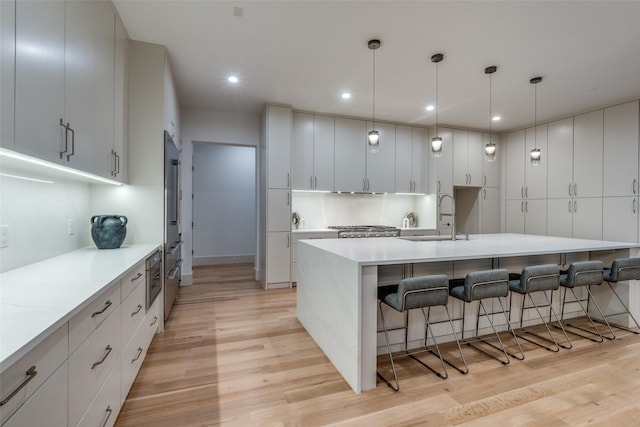 kitchen featuring white cabinets, pendant lighting, light hardwood / wood-style floors, and sink