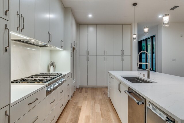 kitchen with white cabinets, pendant lighting, light hardwood / wood-style floors, and sink