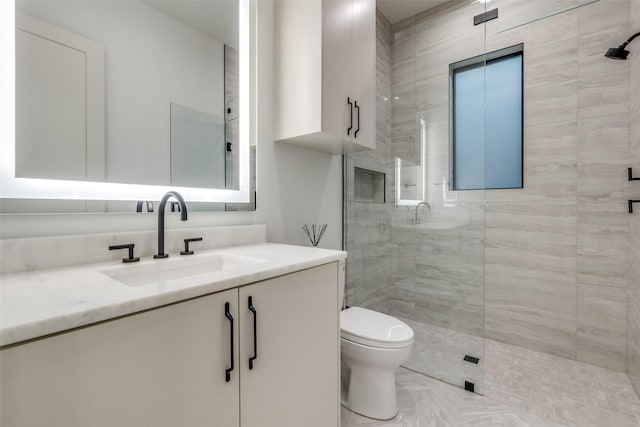 bathroom featuring vanity, toilet, and a tile shower