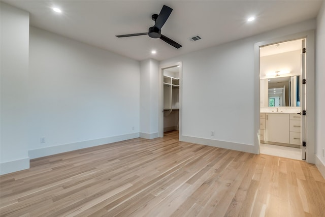 unfurnished bedroom with a walk in closet, ceiling fan, light hardwood / wood-style flooring, connected bathroom, and a closet