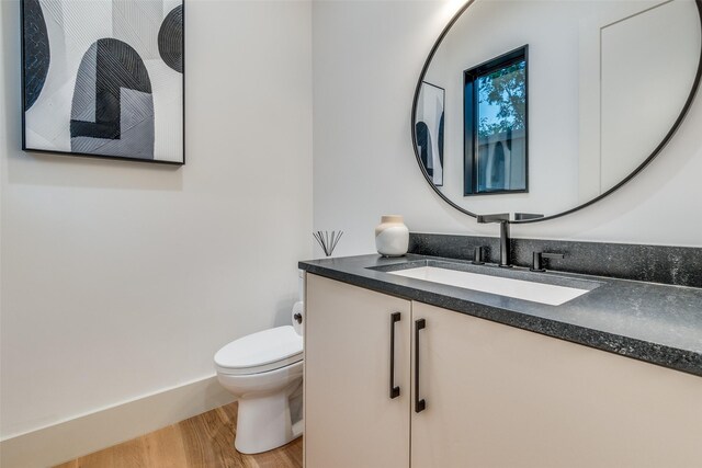 bathroom with toilet, vanity, and hardwood / wood-style flooring