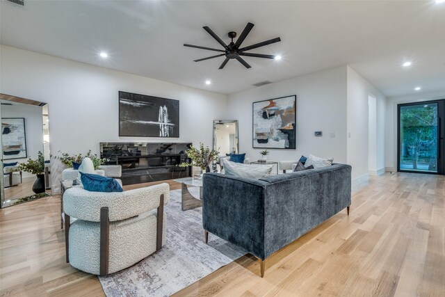 living room featuring a fireplace, ceiling fan, and light hardwood / wood-style flooring