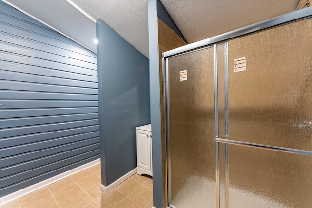 bathroom featuring tile patterned flooring, a textured ceiling, vaulted ceiling, and a shower with shower door