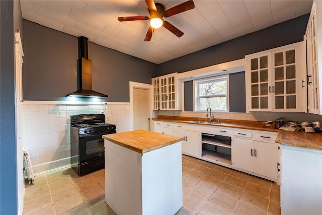 kitchen with wall chimney exhaust hood, sink, black appliances, butcher block countertops, and white cabinetry