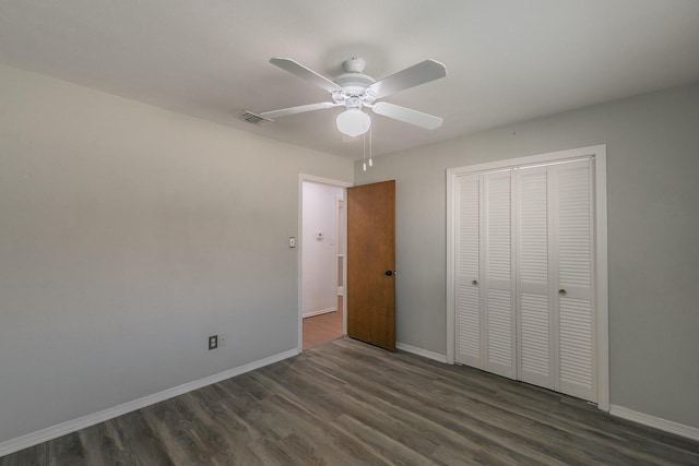 unfurnished bedroom featuring ceiling fan, a closet, and dark wood-type flooring