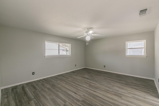 empty room featuring ceiling fan, dark wood-type flooring, and a healthy amount of sunlight