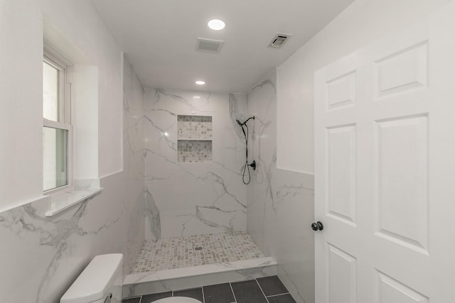 bathroom with tiled shower, toilet, and tile walls