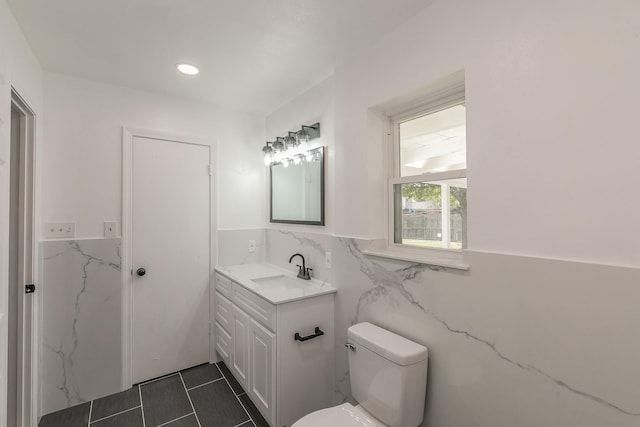 bathroom with vanity, toilet, and tile walls