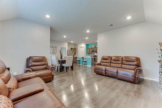 living room with light hardwood / wood-style floors and vaulted ceiling