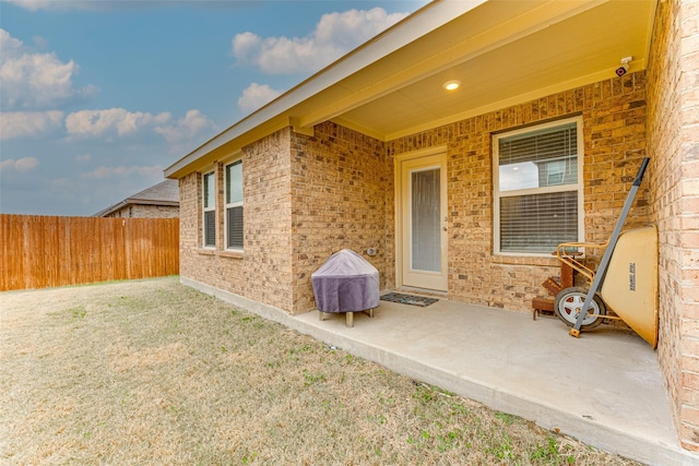 view of exterior entry featuring a lawn and a patio area