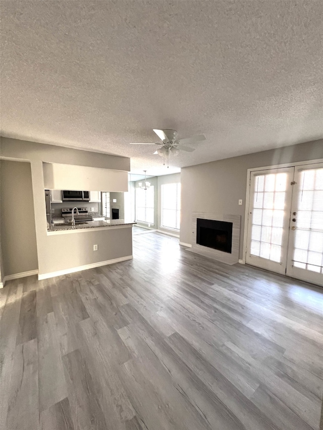 unfurnished living room featuring wood-type flooring, a textured ceiling, and ceiling fan