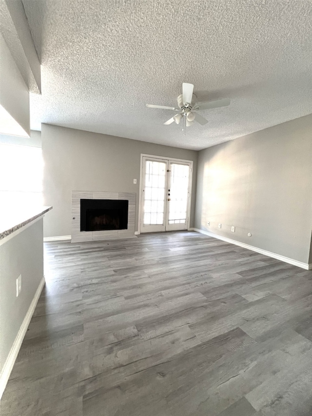 unfurnished living room featuring ceiling fan, french doors, wood-type flooring, and a textured ceiling