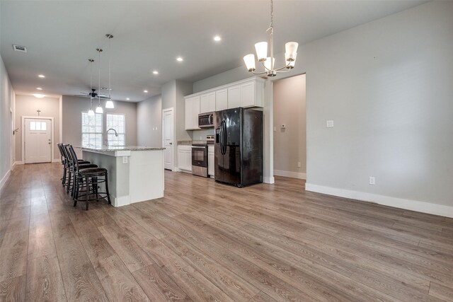 kitchen featuring white cabinetry, stainless steel appliances, decorative light fixtures, a kitchen island with sink, and light wood-type flooring